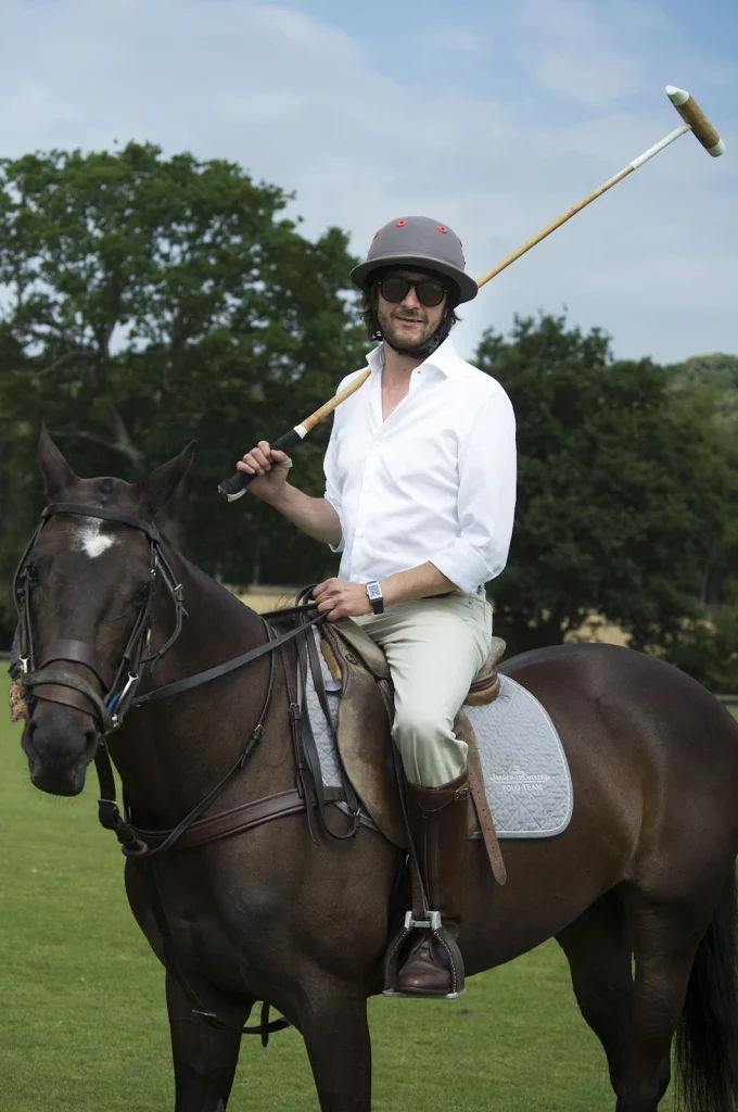 A man confidently rides a horse across an open field, showcasing the bond between rider and animal