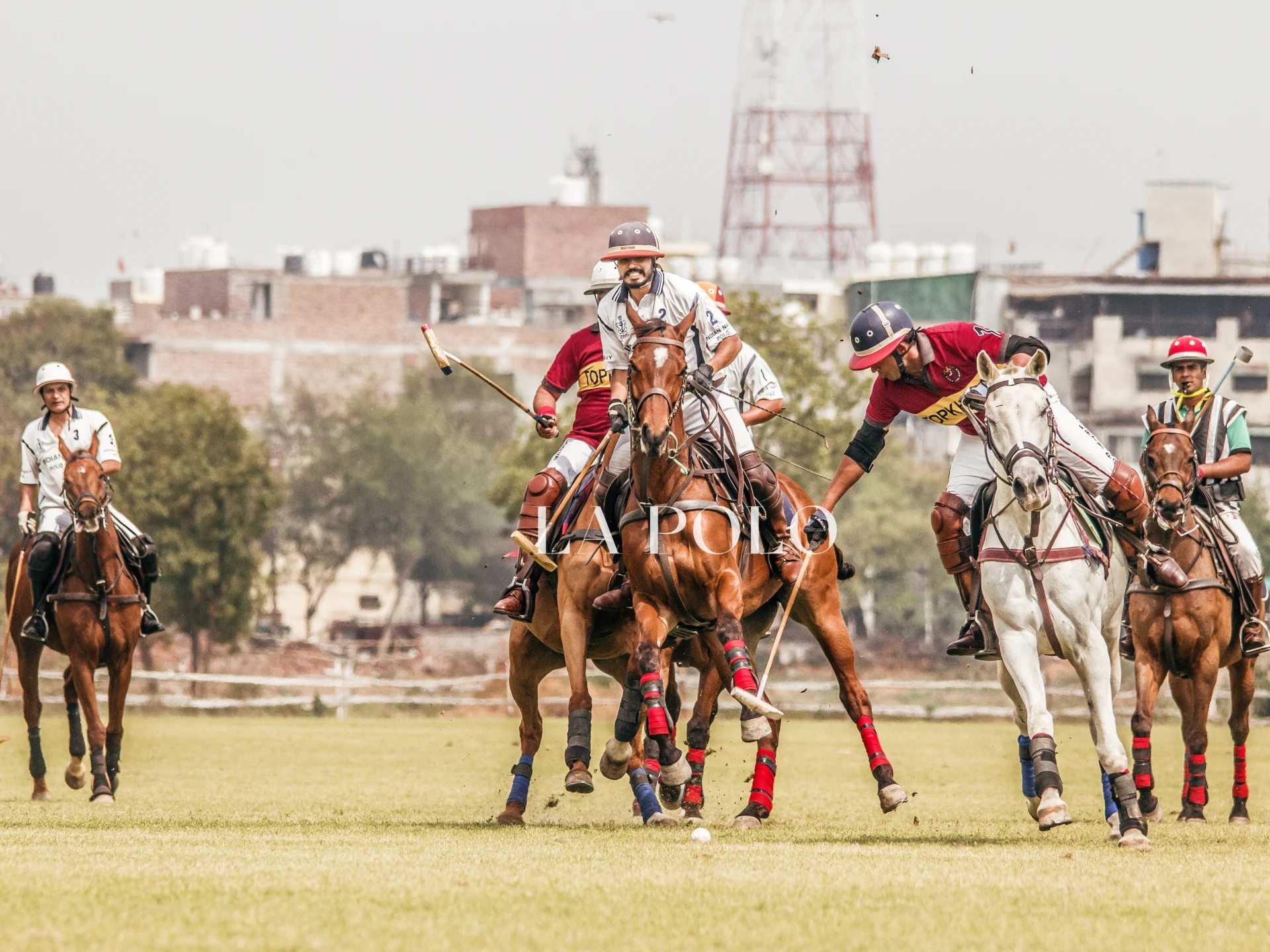 A vibrant polo match with players on horseback, a mix of red and white shirts, competing on a grassy field.