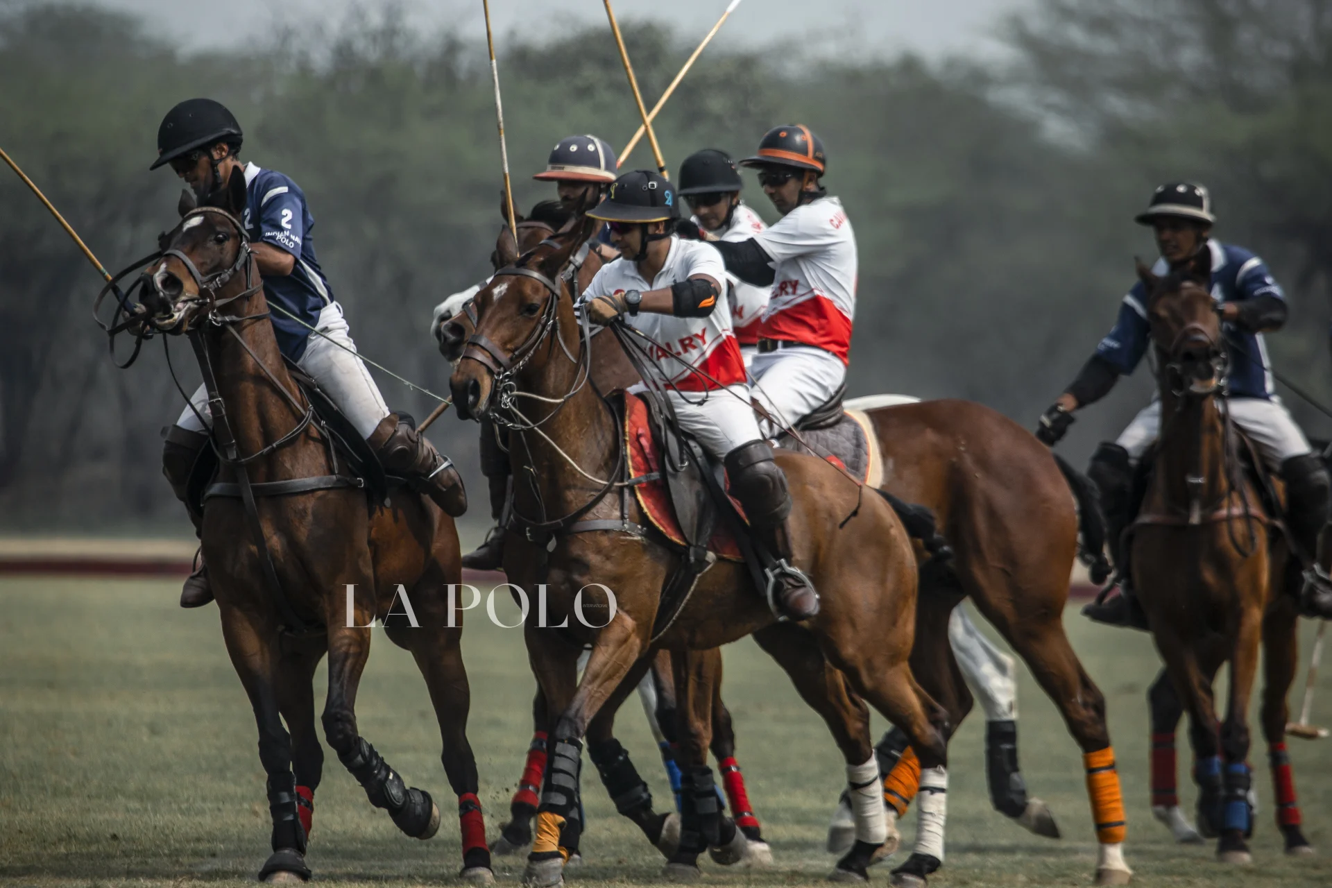 A group of polo players on horseback engage in a thrilling match, wielding mallets under a clear sky.