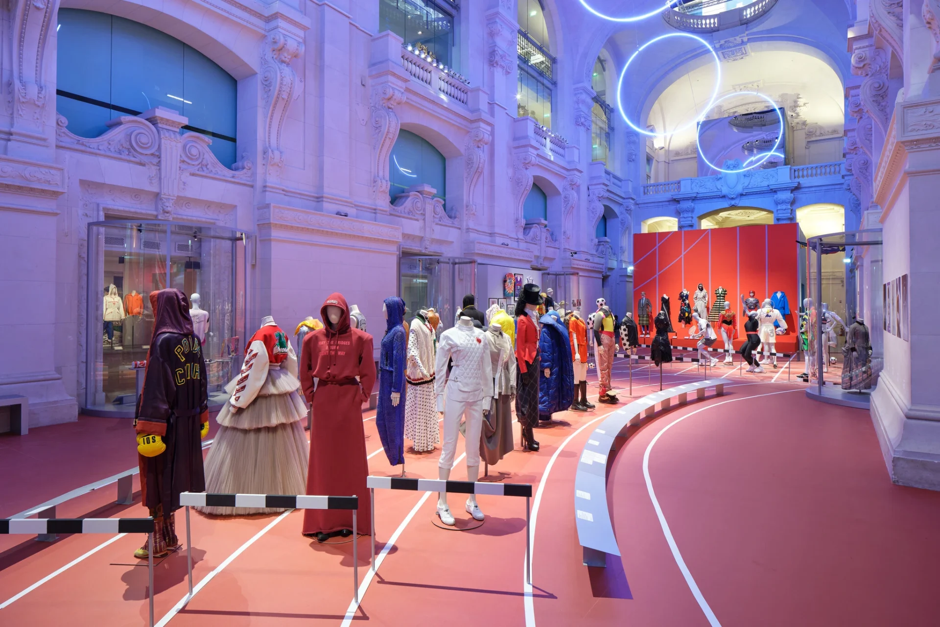 A spacious room filled with various mannequins, showcasing fashion, alongside a large building in the background
