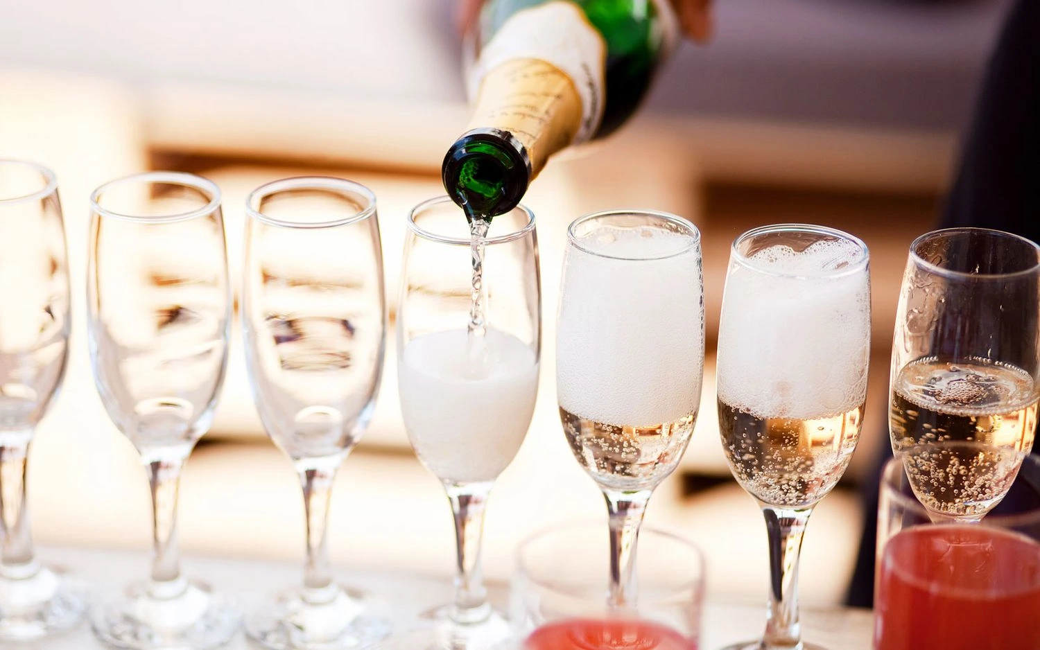 Sparkling wine being poured into elegant flutes, with half-filled glasses creating a festive celebration atmosphere – perfect for parties and special occasions