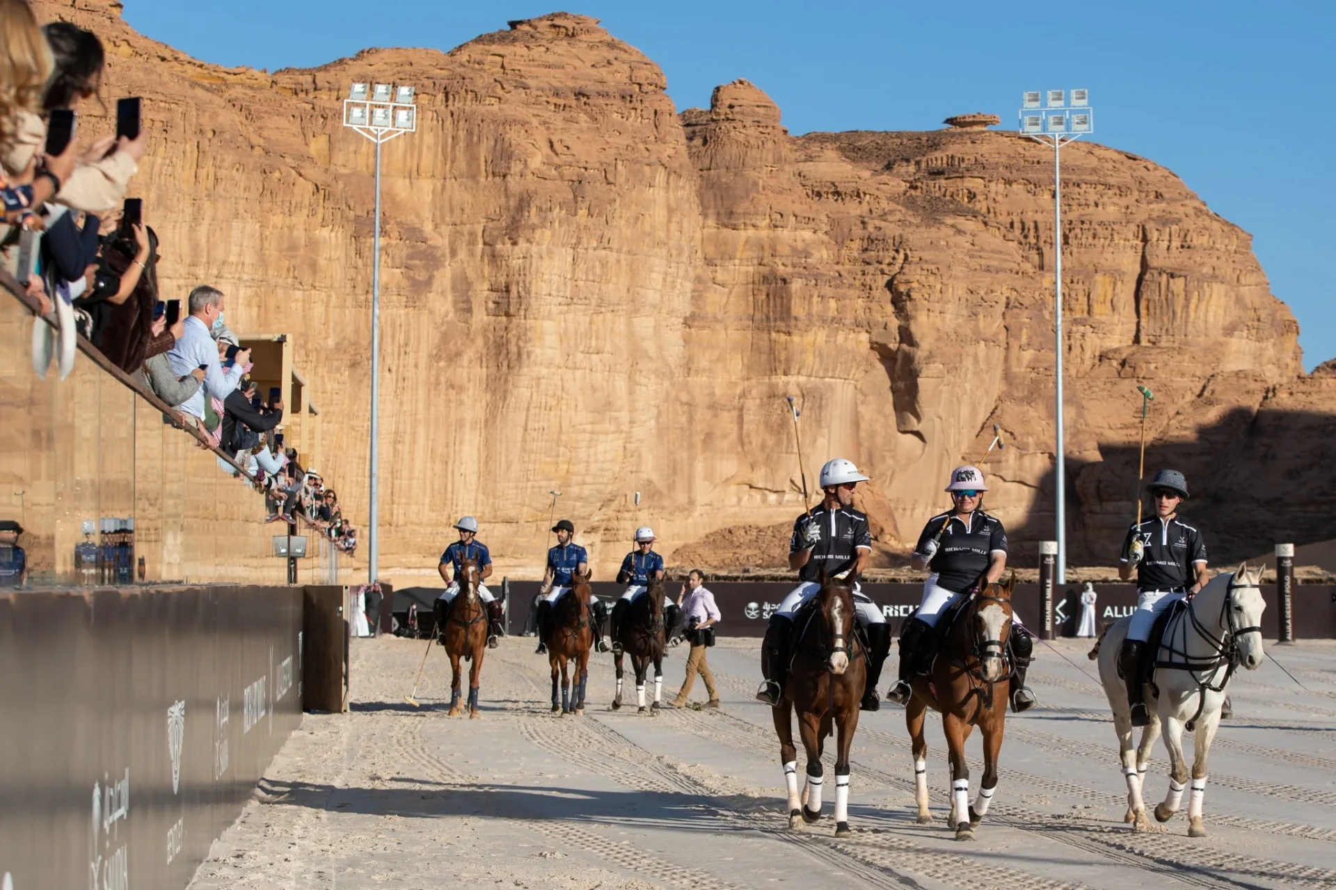 Several riders on horseback navigate a dirt arena, demonstrating their equestrian abilities in a lively outdoor environment