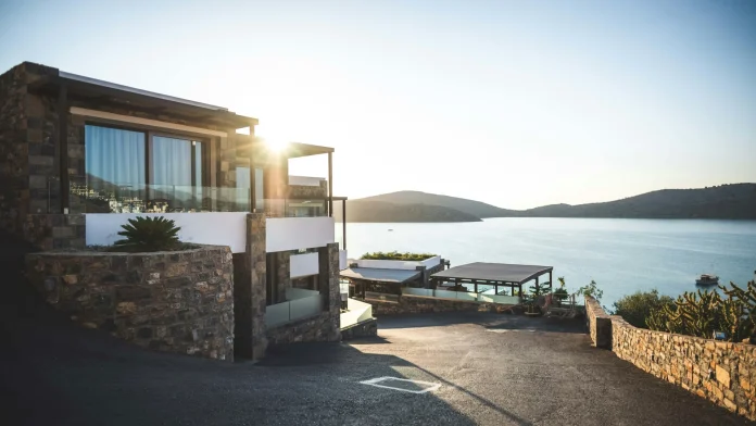 A mountain-side house with a scenic view of the water below, surrounded by natural beauty and tranquility