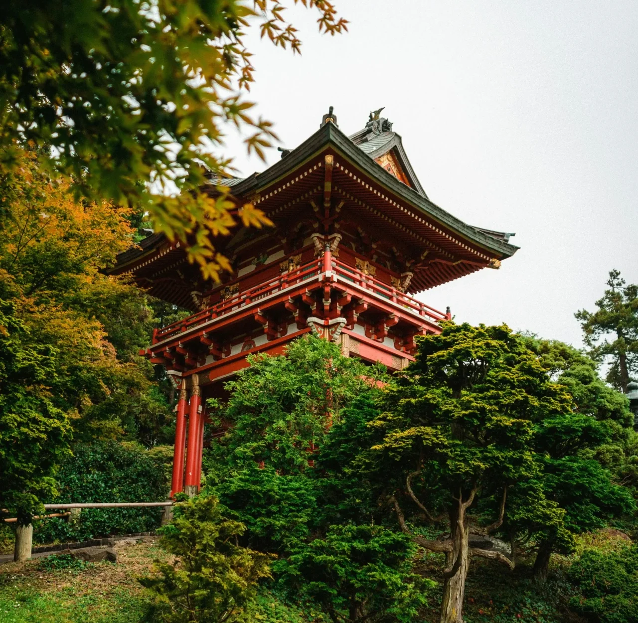 A red pagoda stands gracefully amidst the serene beauty of a traditional Japanese garden